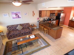 A compact kitchen with a central island, wooden cabinets, and a microwave.