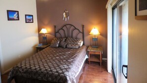 A bedroom with a bed, two bedside tables with lamps, a ceiling fan, and a wall-mounted shelf with a decorative item.