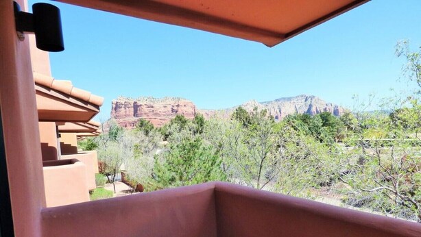 A balcony with a view of red rock formations and sparse vegetation.