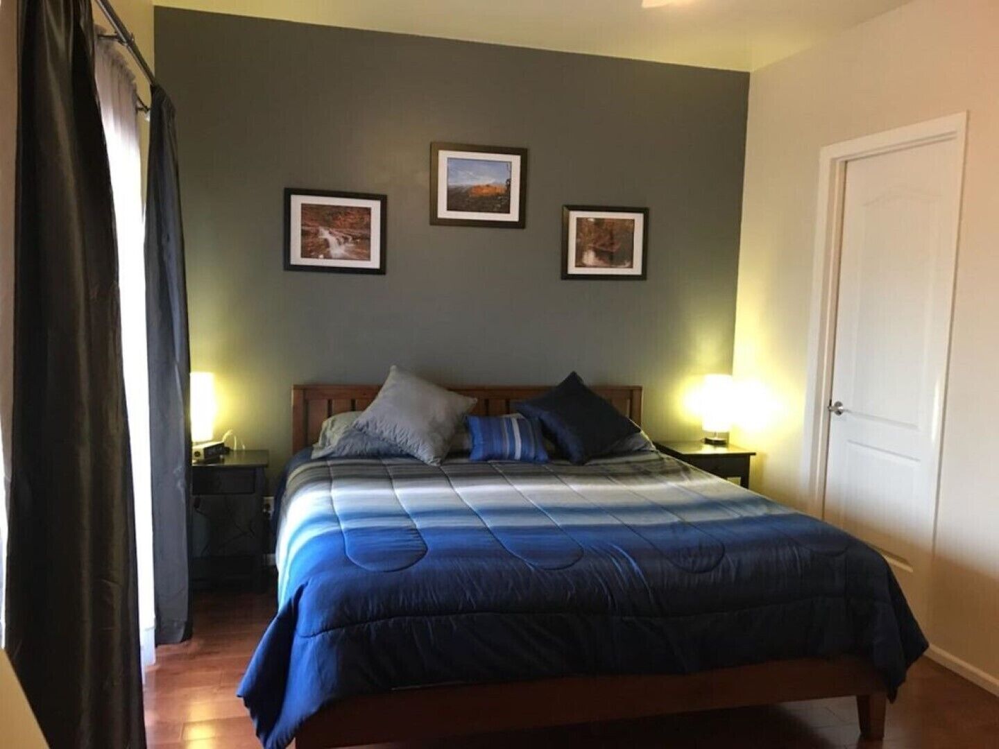 Ein Schlafzimmer mit einem Bett, zwei Nachttischen und drei gerahmten Bildern an der Wand.