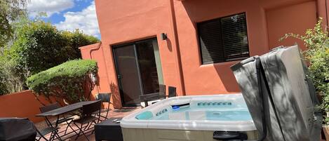 A backyard with a hot tub, patio furniture, and a covered grill area.