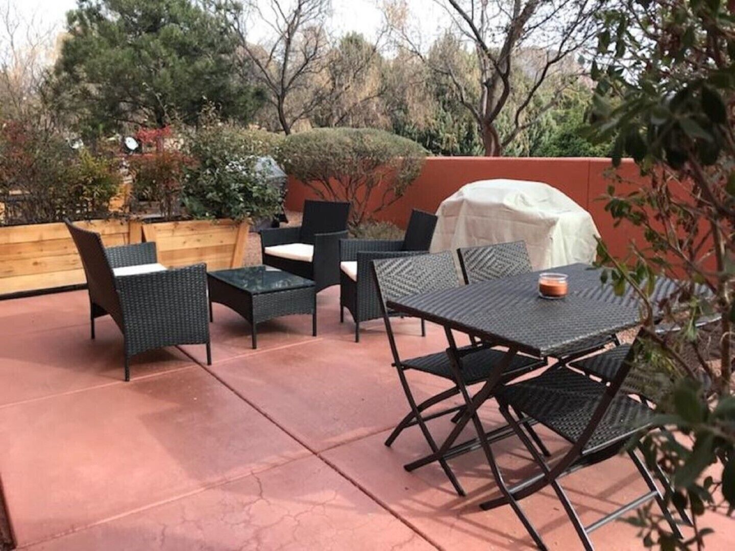 Une terrasse extérieure avec des meubles en osier, une table couverte et un banc en bois.