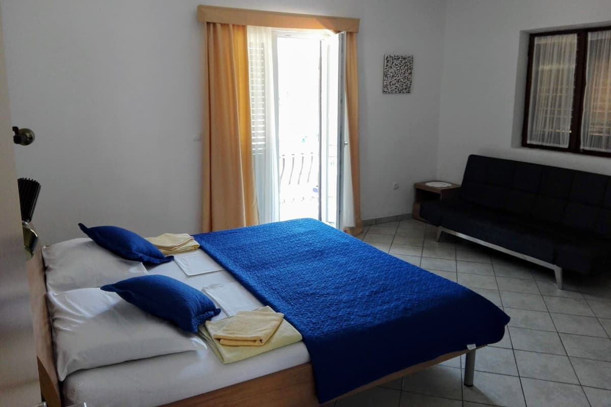 Ein Hotelzimmer mit Bett, Sofa, einem Fenster mit Vorhängen und einem Wandbild.