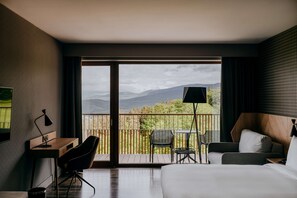 A hotel room with a large balcony, a desk, a chair, a bed, and a view of mountains. - Radisson Hotel Szklarska Poręba (Szklarska Poreba)