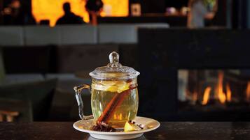 Une théière en verre transparent, munie d’un couvercle, posée sur une soucoupe blanche, elle-même placée sur une table en marbre foncé.