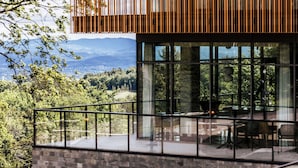 A modern building with large glass windows, a balcony with a metal railing, and a view of a forested landscape. - Radisson Hotel Szklarska Poręba (Szklarska Poreba)