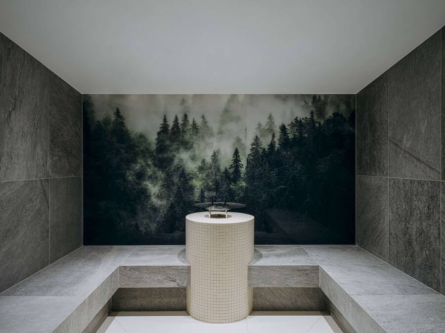 A modern bathroom with a large, grid-patterned sink, a bench, and a forest-themed mural on the wall.