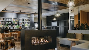 A modern bar area with a fireplace, seating, and a variety of bottles on shelves. - Radisson Hotel Szklarska Poręba (Szklarska Poreba)