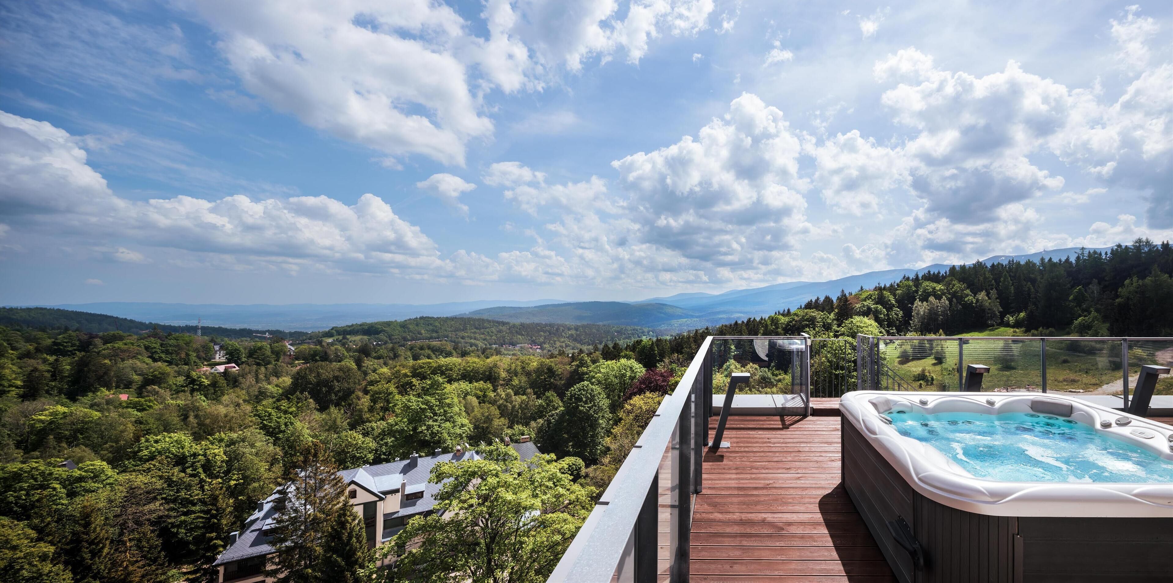 A wooden deck with a hot tub overlooking a mountainous landscape.