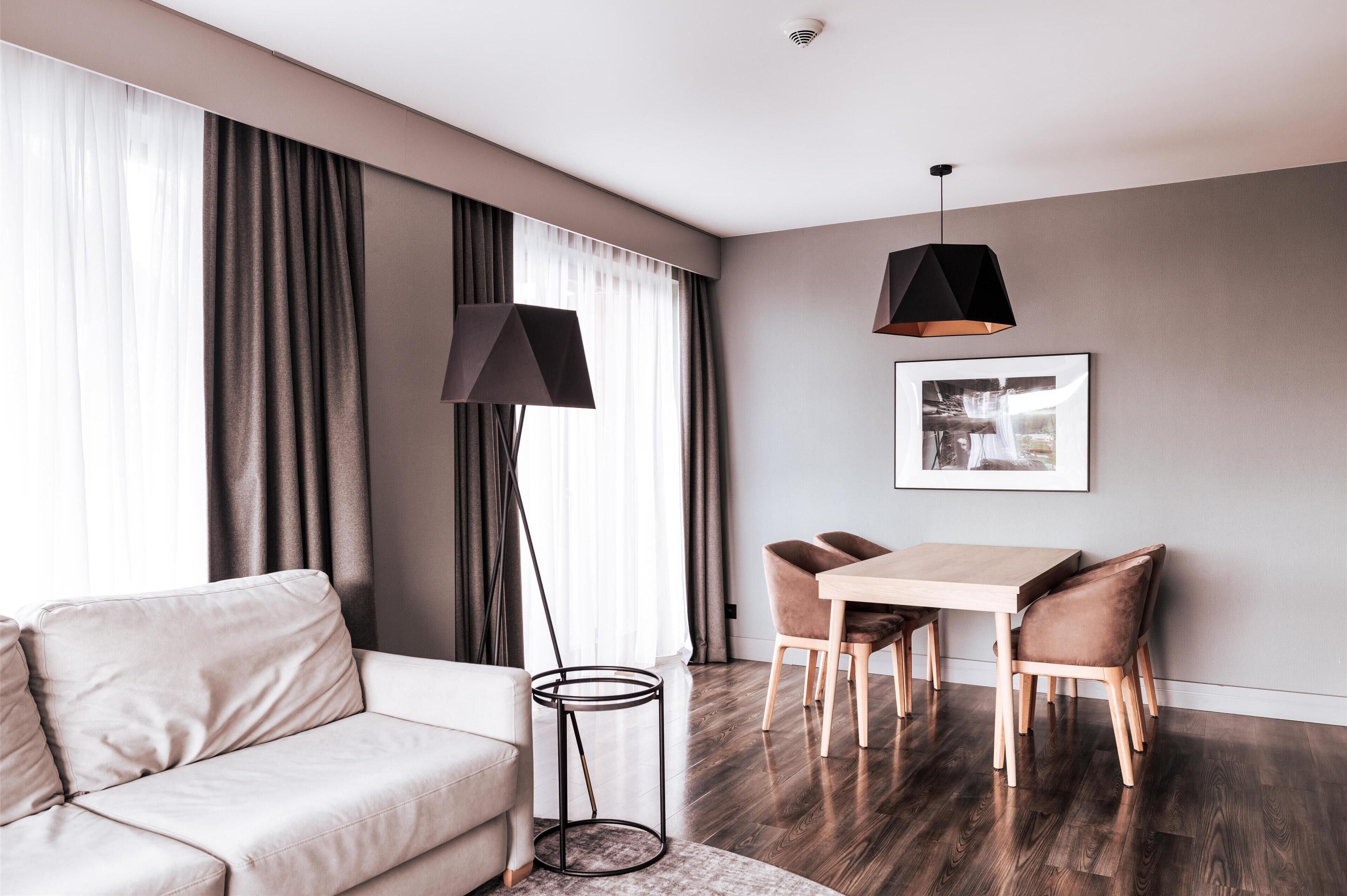 A modern living room with a sofa, dining table, chairs, and a floor lamp.