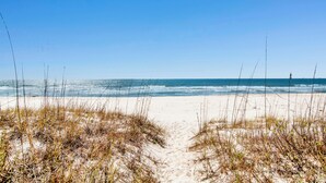 Ein Strandweg, der zum Meer führt, bei blauem Himmel.