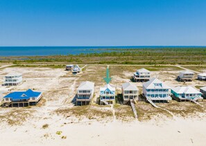 A beachfront property with multiple beach houses, a clear view of the ocean, and a sandy landscape. - Beachfront | Pet Friendly | Private Beach | Gulf Views (Gulf Shores)