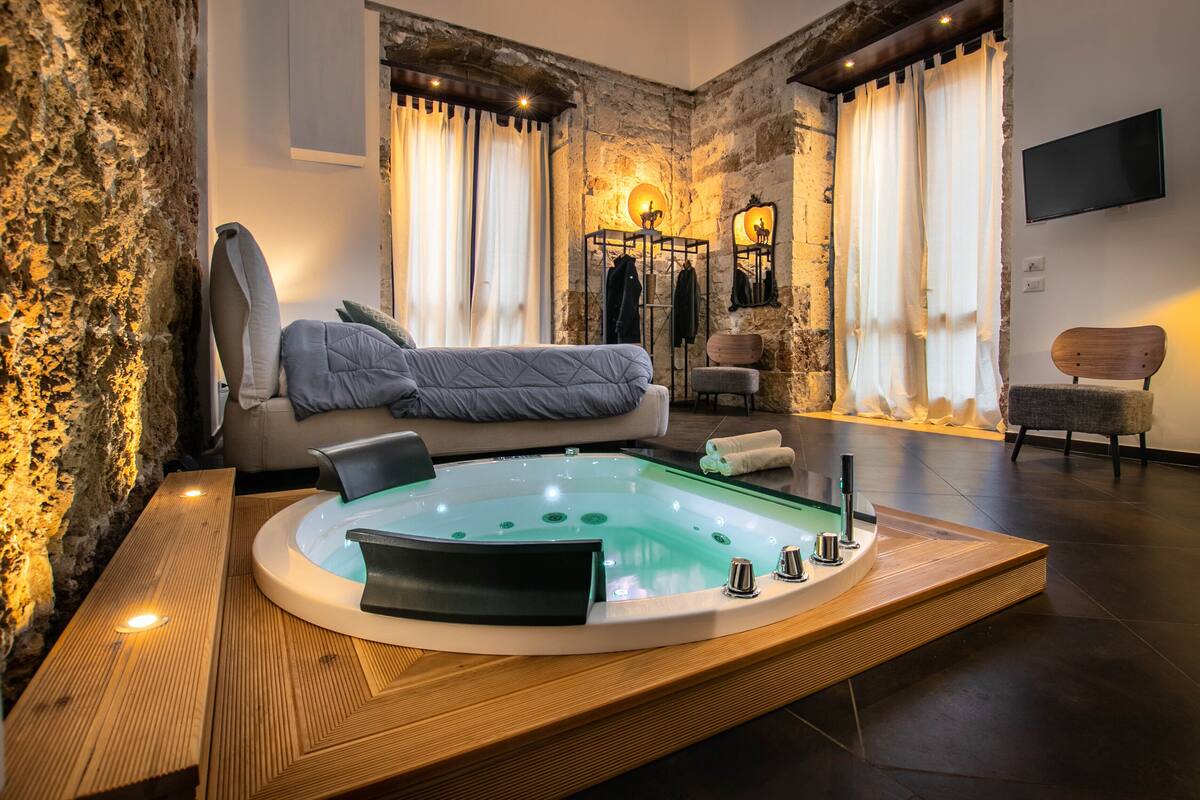 A modern bathroom with a freestanding bathtub, a wooden vanity, and a seating area with a sofa and armchairs.