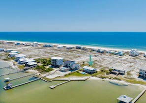 A coastal property with multiple buildings, a dock, and a clear view of the ocean. - Lagoon Front Oasis | Private Heated Pool | Pet Friendly Retreat (Gulf Shores)
