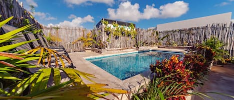 Una piscina al aire libre, sombrillas, sillones reclinables de piscina