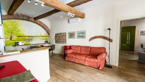 A room with a wooden ceiling, a red sofa, a white desk with a computer, and a mural of a landscape. - Casa Agli Scrimiari ItalianFlat (Verona)