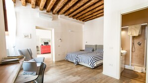 A bedroom with a bed, a desk with a chair, and a shower area. - Casa Agli Scrimiari ItalianFlat (Verona)