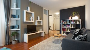 A modern living room with a grey sofa, a flat-screen TV, and a white bookshelf. - Rupa pod oblacima (Zagreb)