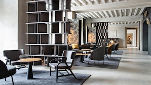 Un interior moderno con un mostrador de recepción alargado, una zona de estar y una pared decorativa con un diseño geométrico.