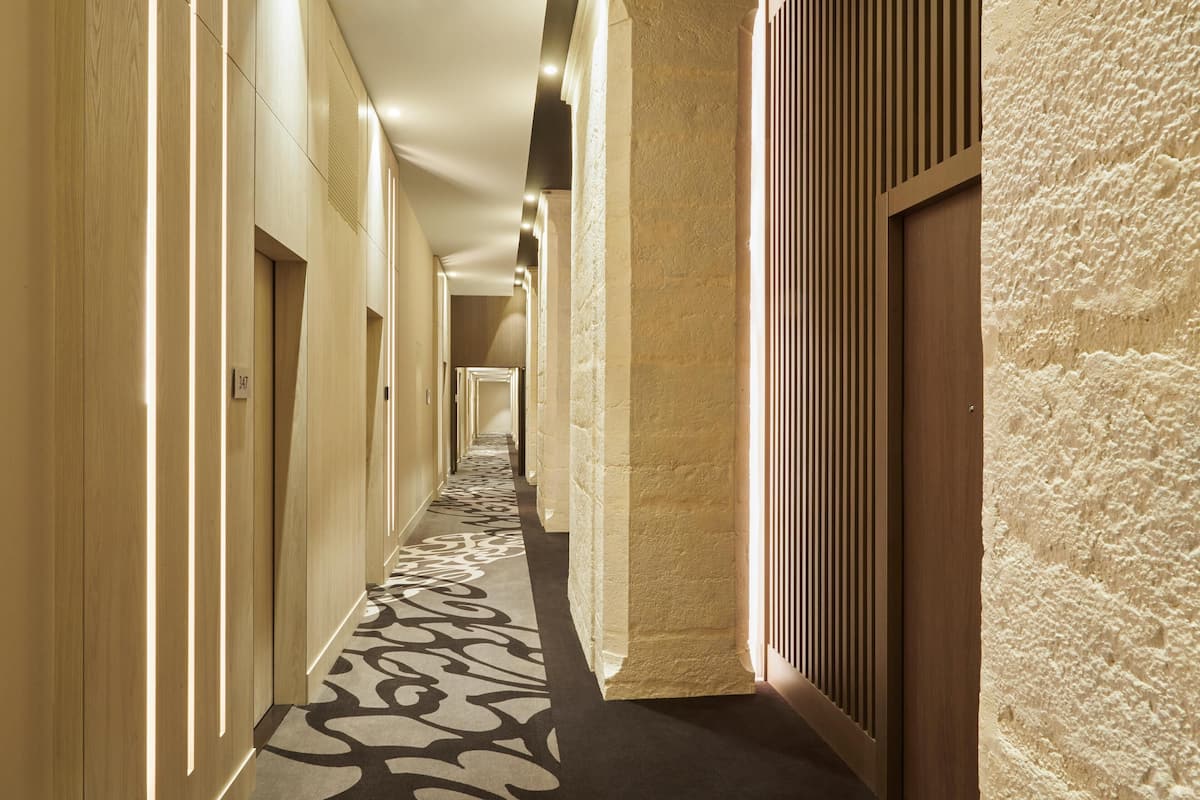 A long, narrow hallway with wooden paneling and a patterned carpet.