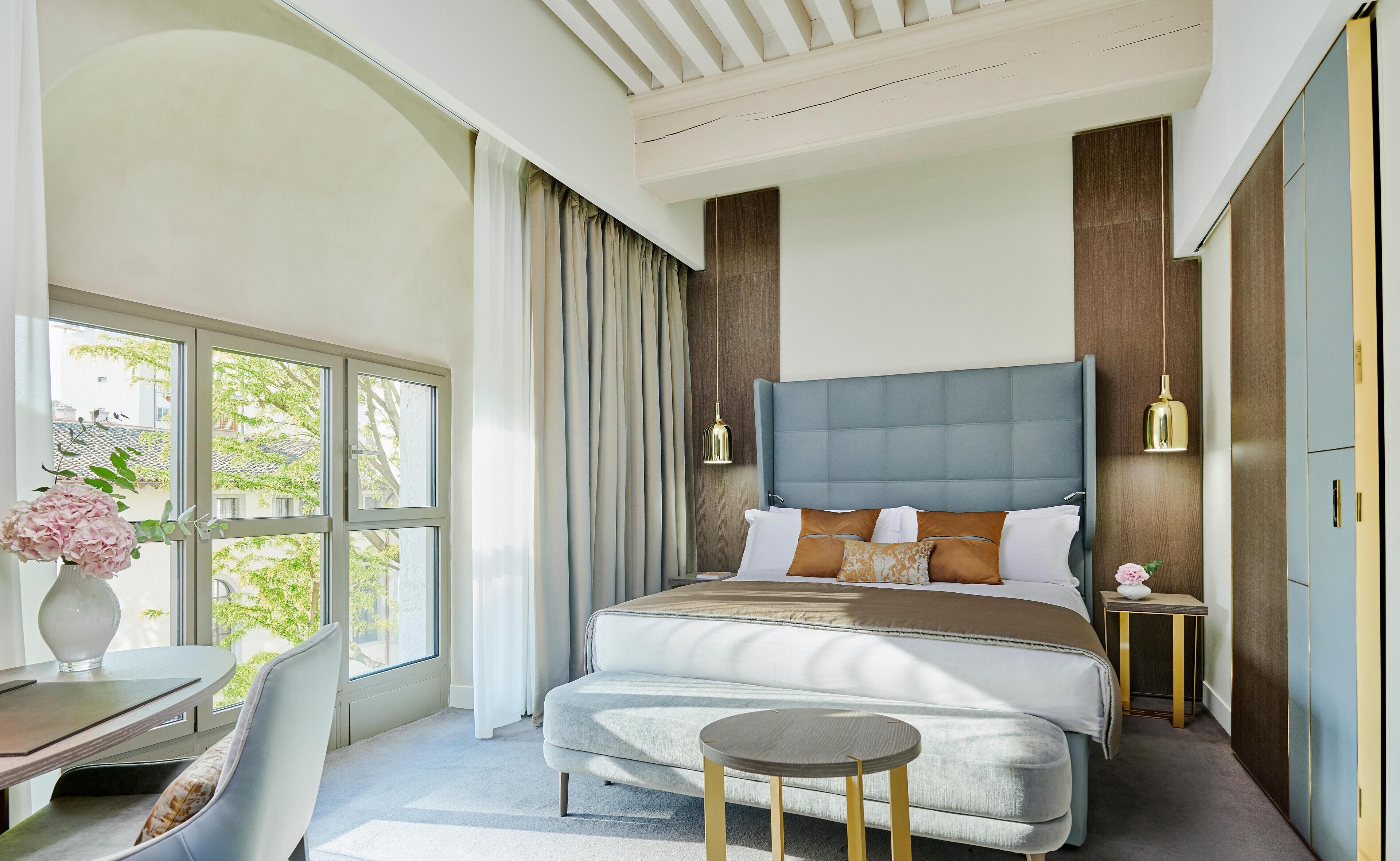A modern bedroom with a large bed, a desk, and a chair.