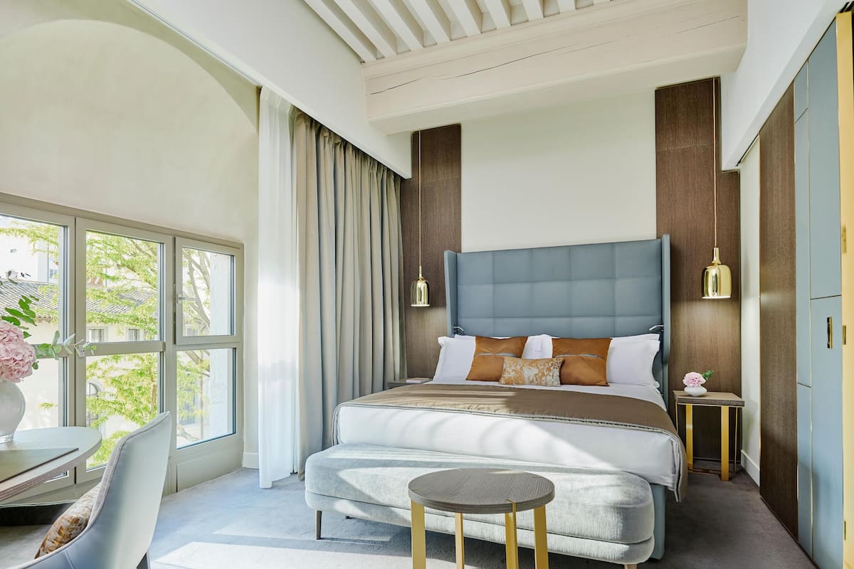A modern bedroom with a large bed, a desk, and a chair.