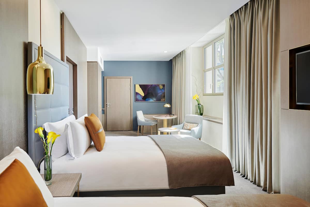 A modern hotel room with a large bed, a desk, and a television.