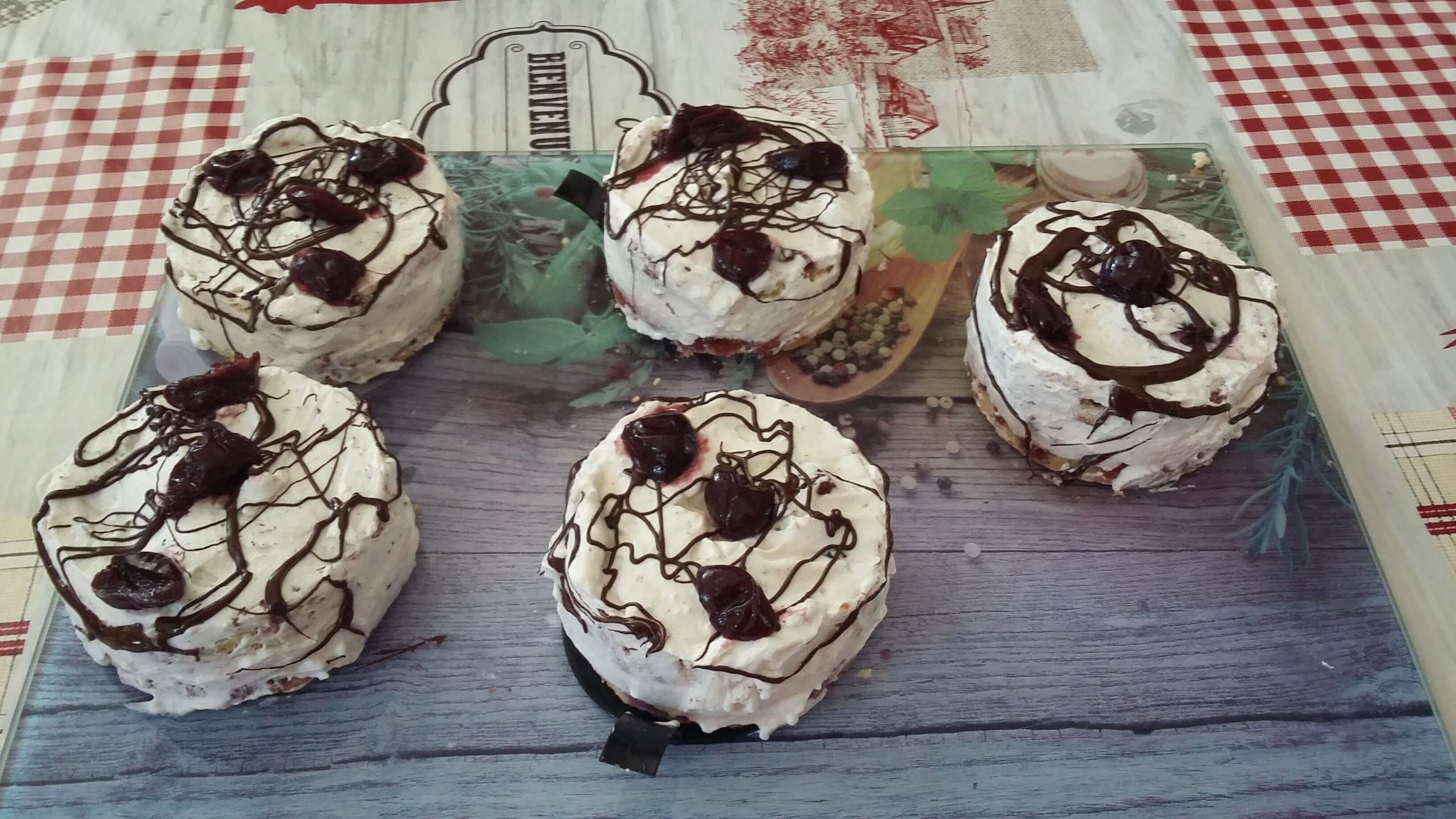 Cuatro postres sobre una mesa de madera con mantel a cuadros.