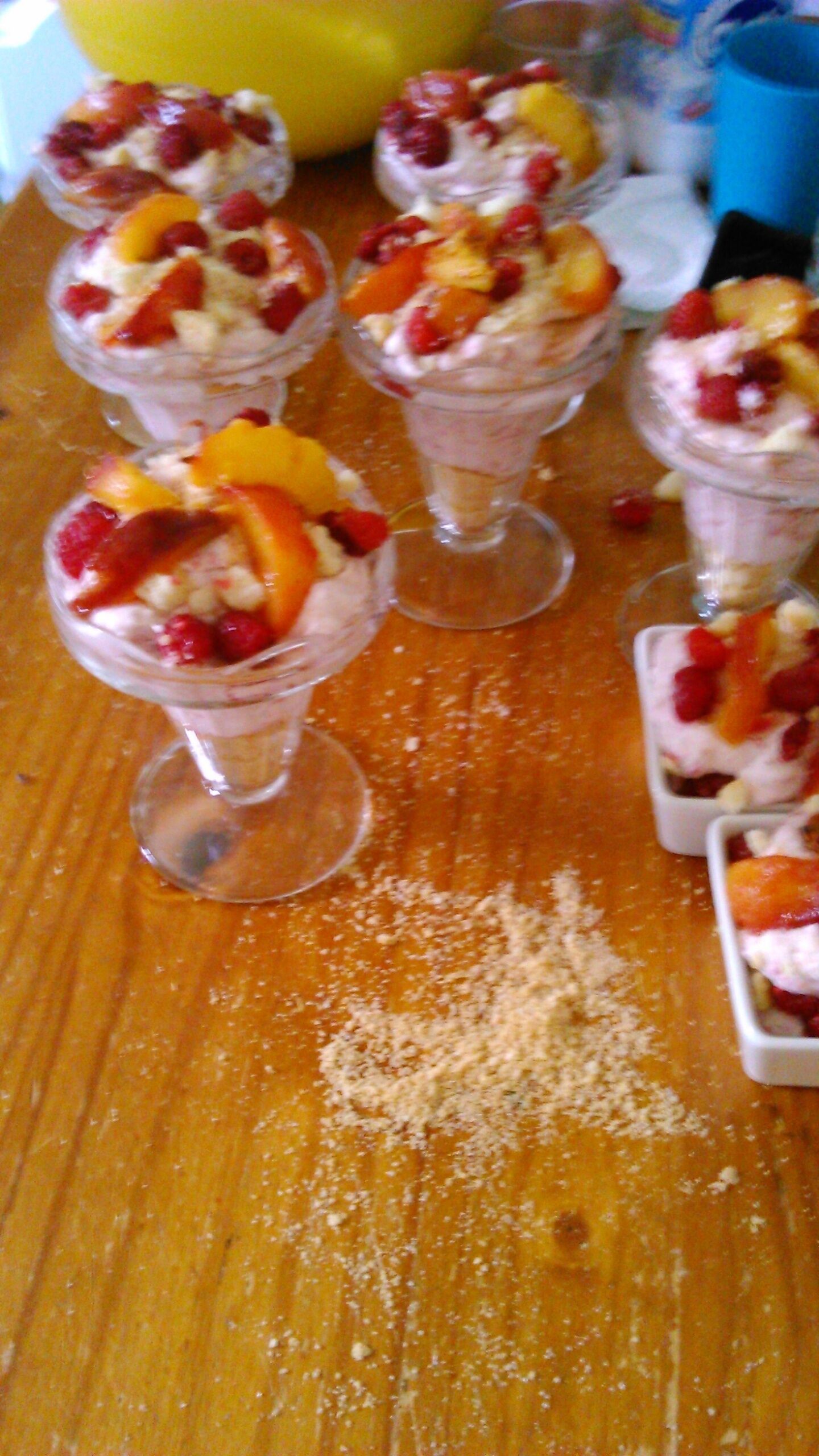 Dessertglas med frukt som topping, placerade på ett träbord.