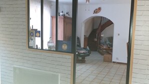 A room with a tiled floor, a wooden cabinet, a chair, and a table with various items on it. - La Chti Cabane (Taintrux)