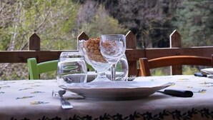 A dining table set outdoors with a view of a forested area. - La Chti Cabane (Taintrux)