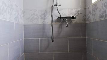 Een douchehoek met douchekop en handdouche.