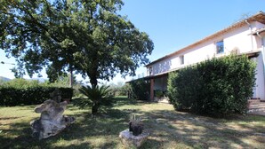 Una casa con jardín, un árbol grande y una escultura de piedra.