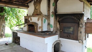 Una cocina rústica al aire libre con horno de leña, horno de ladrillo y chimenea.