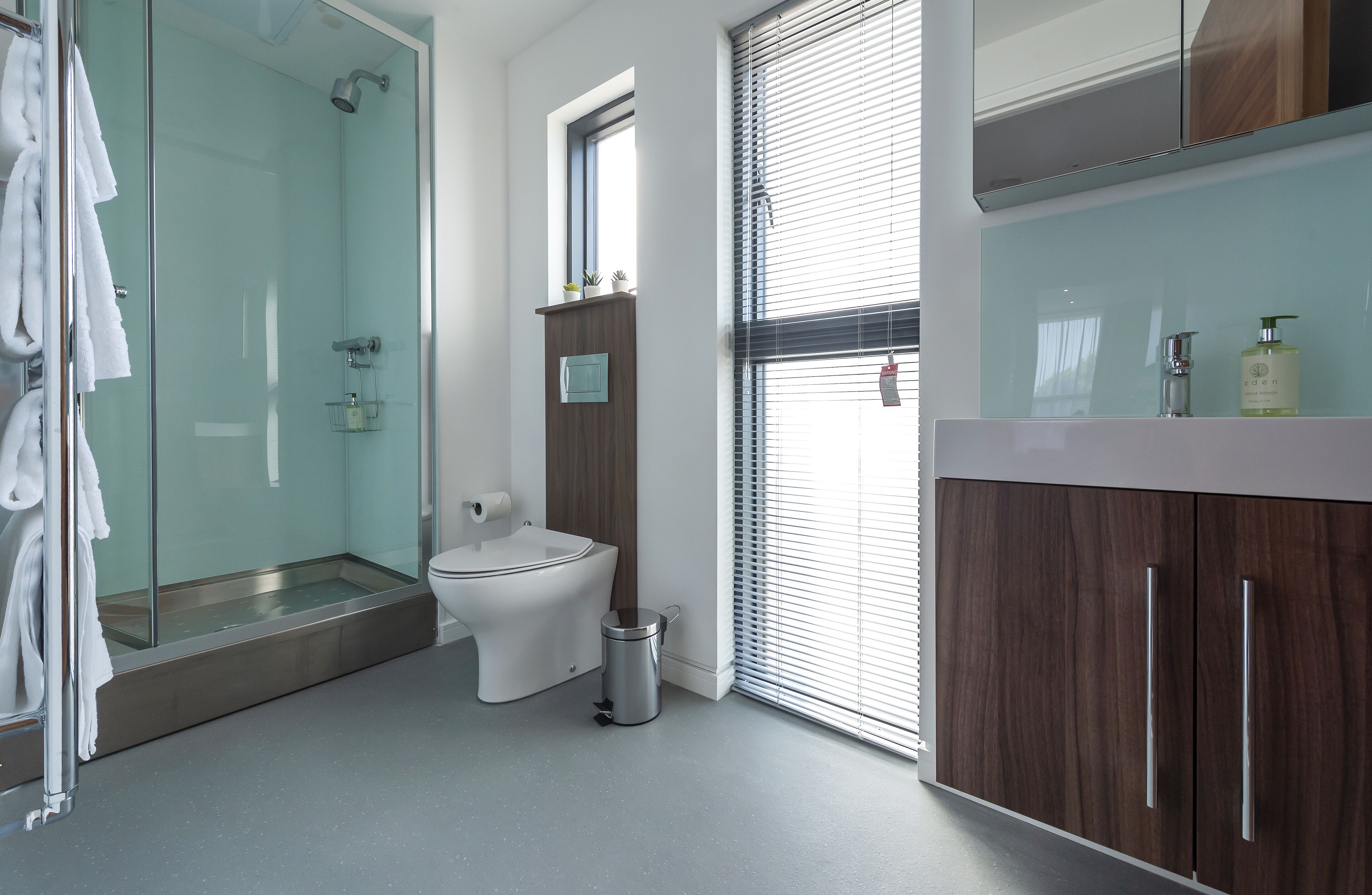 Une salle de bain moderne dotée d’une douche à parois de verre, de toilettes et d’un meuble-lavabo avec un miroir.