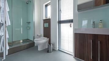 Une salle de bain moderne dotée d’une douche à parois de verre, de toilettes et d’un meuble-lavabo avec un miroir.