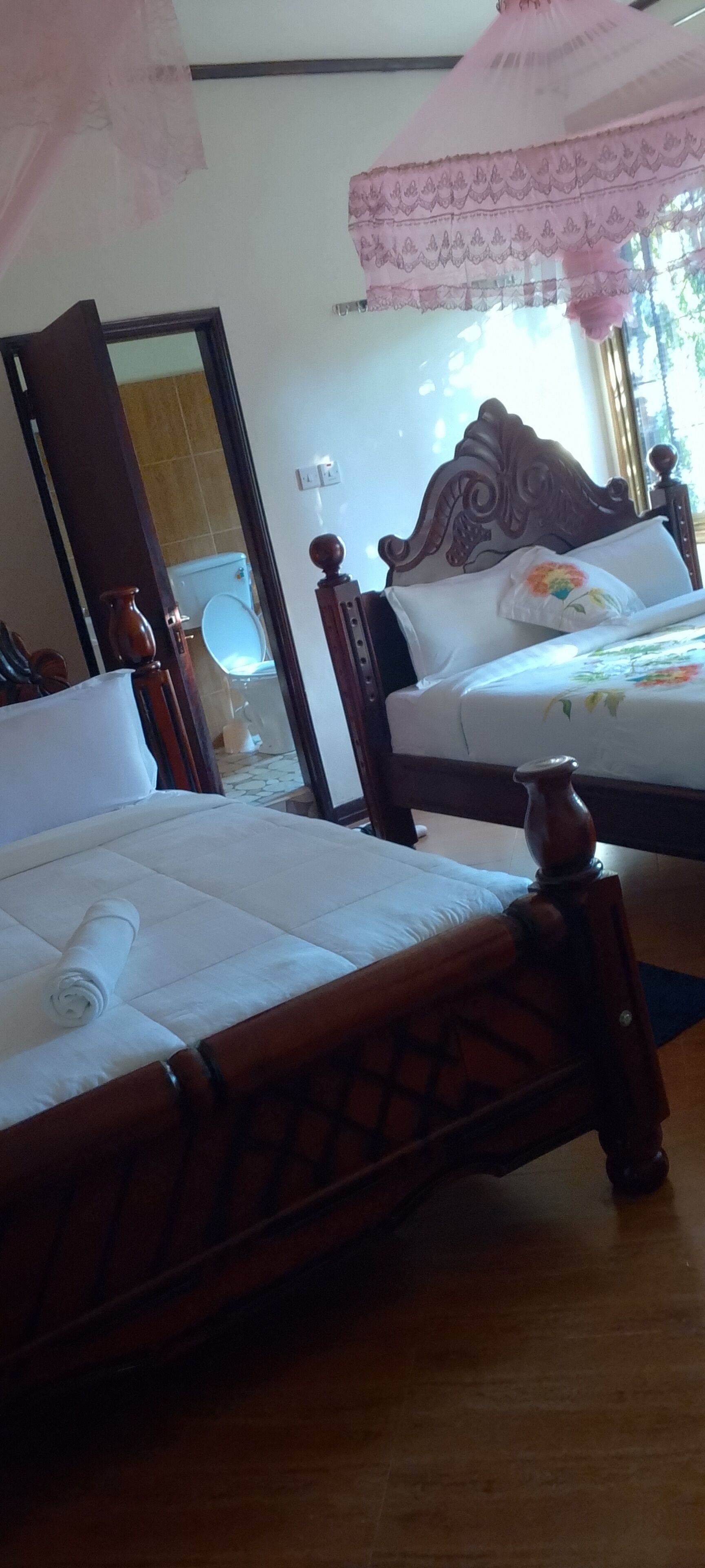 A bedroom with two beds, wooden headboards, and a mirror.