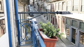 A narrow street with buildings on either side, a blue metal railing, and a potted plant. - Clérigos Apartments (Porto)