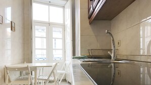A kitchen with white cabinetry, a black countertop, and a window with a view of the outside. - Clérigos Apartments (Porto)