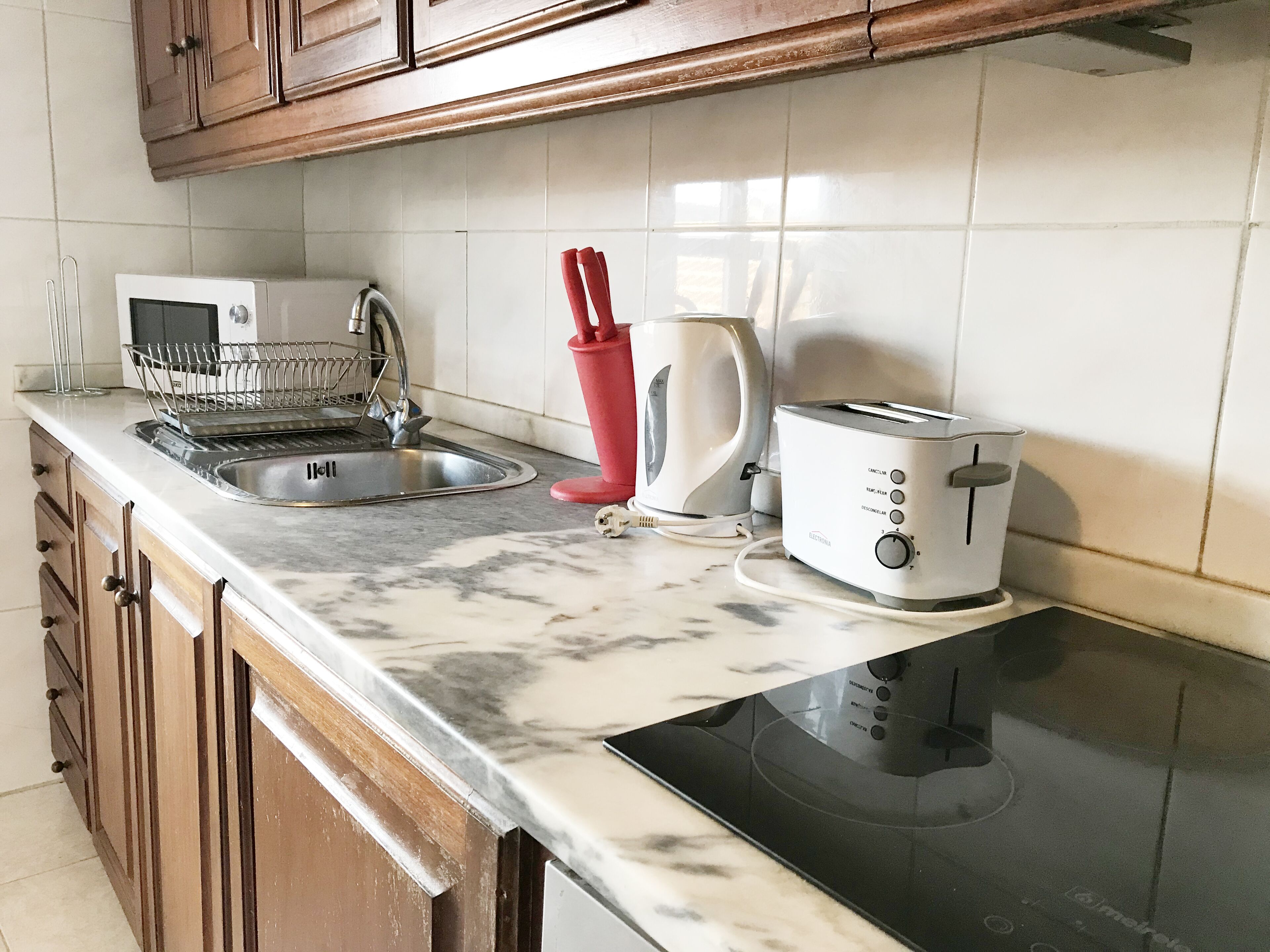 A kitchen with a sink, a toaster, and a kettle.