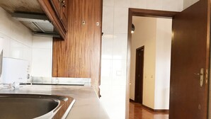 A kitchen with a large countertop, a sink, and wooden cabinets. - Clérigos Apartments (Porto)