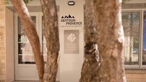 En skylt för VentoX-Provence, en del av det franska turistinformationsnätverket, med en modern byggnadsfasad och en entré av glas.