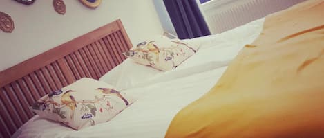 A bed with two pillows, a wooden headboard, and a window with curtains.