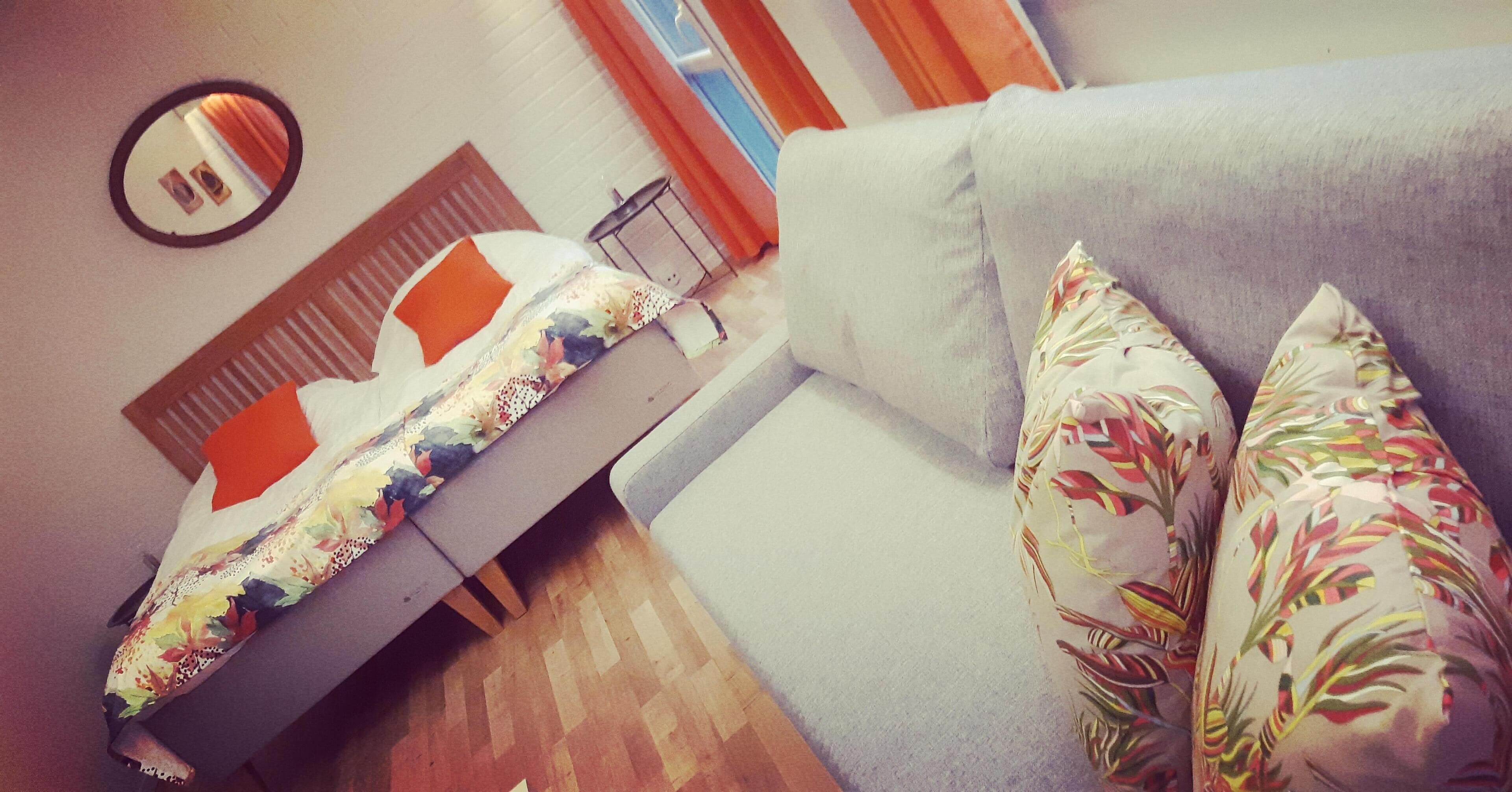 A bedroom with a bed, a sofa, and a mirror on the wall.