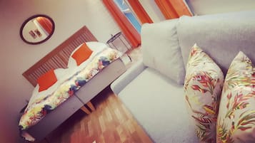 A bedroom with a bed, a sofa, and a mirror on the wall.