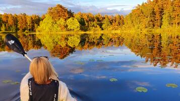 A person kayaking on a calm lake with reflections of trees and sky.