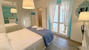 A hotel room with a bed, a mirror, a window with curtains, and a door. - House Villino Azzurro at 50 meters from the beach (Marina di Grosseto)