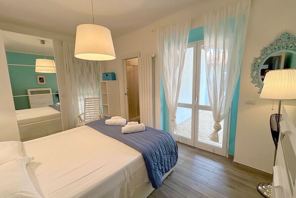 Ein Hotelzimmer mit Bett, Spiegel, Fenster mit Vorhängen und einer Tür.