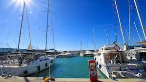 A marina with multiple sailboats docked, a clear blue sky, and the sun shining brightly. - House Villino Azzurro at 50 meters from the beach (Marina di Grosseto)