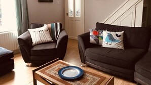 Ein Wohnzimmer mit zwei dunklen Sofas, einem Couchtisch und einer Tür mit Kunstwerk.